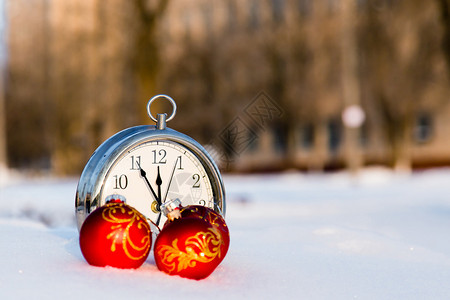 3个红圣诞节球和雪上的钟表新年贺卡概图片