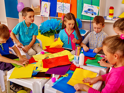 儿童群体正在用小学桌上的彩色纸做一些东西图片