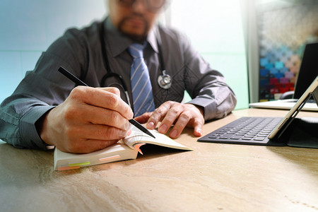 医生在笔记本和数字平板电脑键盘与大理石台手提笔记本机对接时写字图片