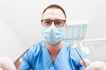 戴面罩的Hygienist带着微笑和友好的专业工具提供咨图片