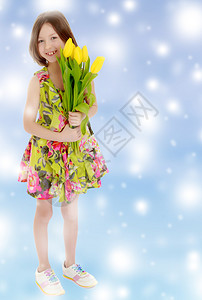 穿着暑期服的可爱的白人女孩拿着一束黄色郁金香花图片