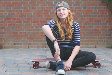 一个很酷的年轻女孩在户外玩滑板的肖像图片