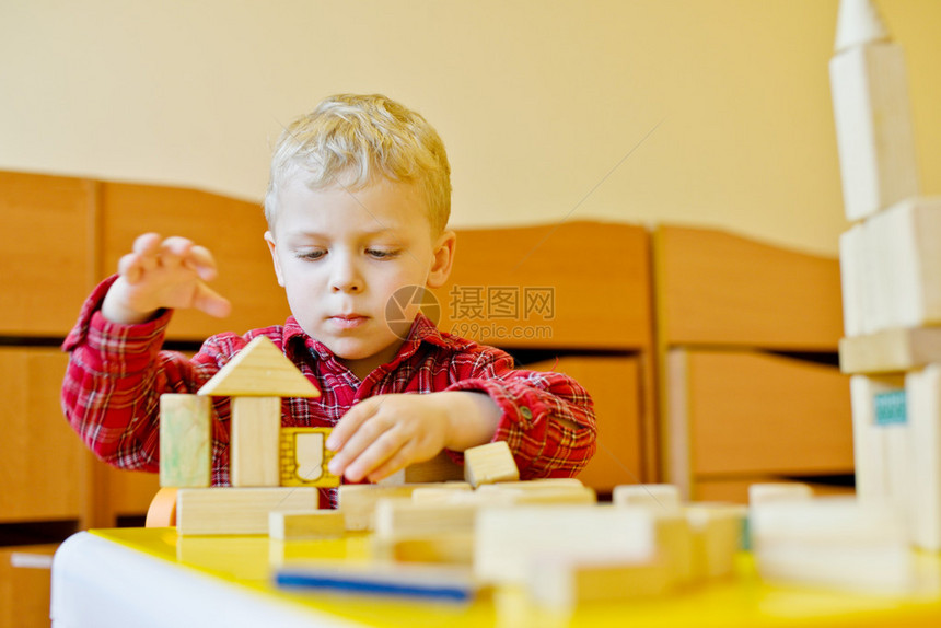 蹒跚学步的男孩在桌子上玩积木图片