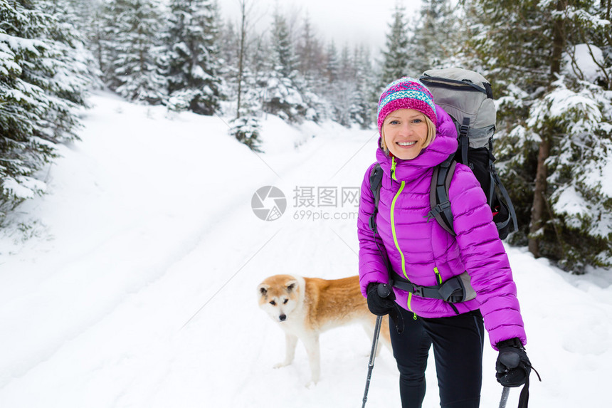 女人带着秋田犬在白色的冬季森林里徒步旅行在白雪皑的寒冷大自然中户外休闲健身和健康生活方式动机和鼓舞人图片