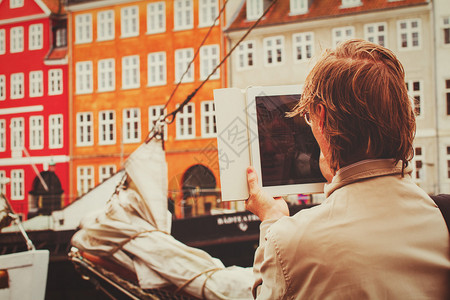年轻旅游青年在哥本哈根大楼的触碰板上拍摄照背景图片