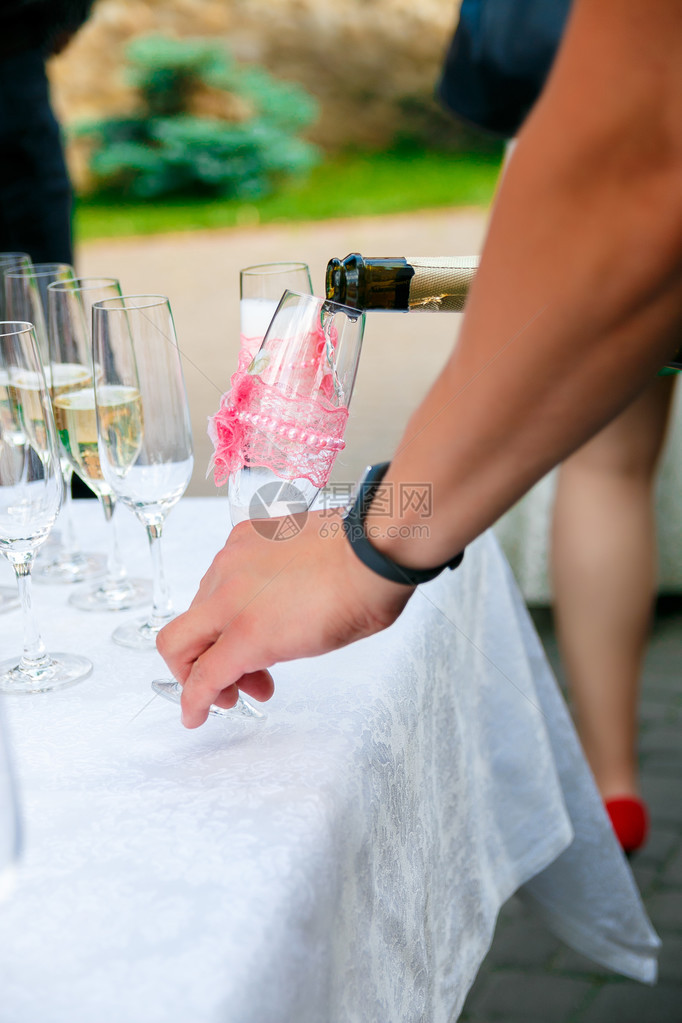 男人的手在酒杯里倒香槟酒杯图片