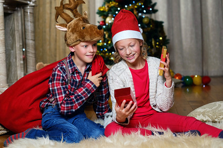 戴着圣诞鹿帽的令人兴奋的可爱男孩和快乐的女孩在圣诞装饰的房图片