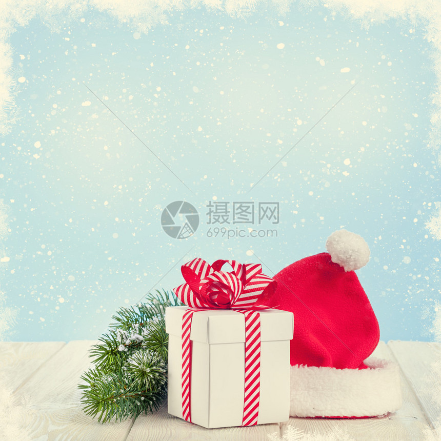 圣诞礼品盒圣塔帽和木桌上的fir树枝图片
