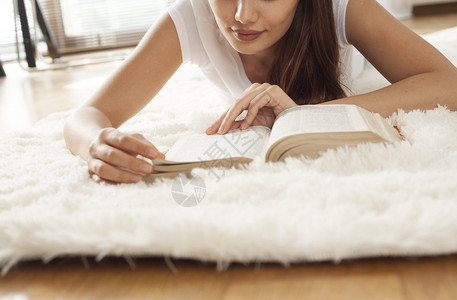 在地毯上看书的年轻女人背景图片