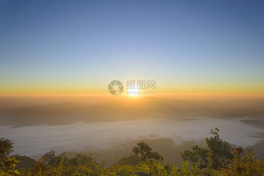 太阳升起在雾之国的山上图片