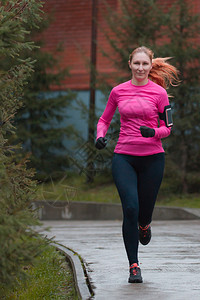 在秋天公园跑步的粉色女子户外女跑步者健康生活方式高图片