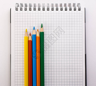 白色背景特写上的笔记本和彩色铅笔图片