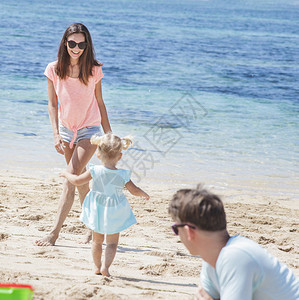 有女儿和丈夫的年轻母亲与女儿和丈夫一起在海图片