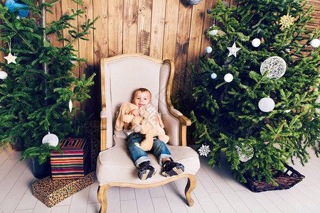 在圣诞树旁边玩具的小男孩图片