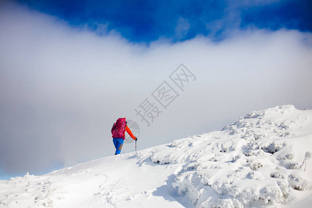 山上冬季节日蓝天空背景的雪坡上走着图片