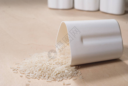 散落在木制表面的稻米白容器中的稻米谷类健康饮食图片