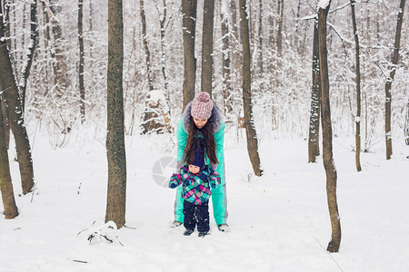 快乐的家庭母亲和女婴在冬季雪地户外玩耍和嘲笑图片