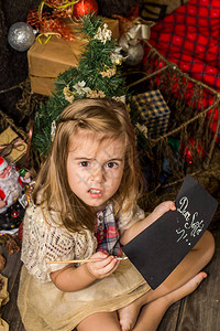 漂亮可爱的小女孩在木地板上的圣诞装饰附近给图片