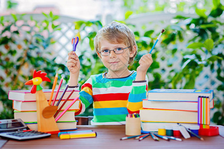 戴着眼镜的滑稽可爱的小男孩拿着蜡笔快乐的孩子和学生回到学校教育学图片