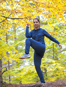伸展和锻炼年轻的运动适合女孩做户外运动积极的女人花时间在秋季森林图片