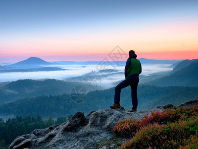 岩上山人看守着奶油薄雾和的早晨风景图片