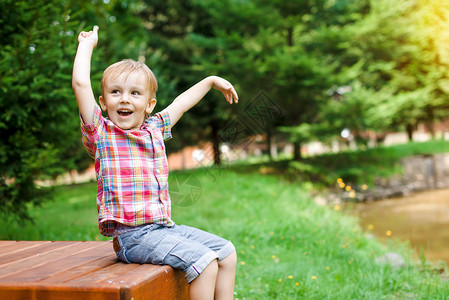 坐在湖边长凳上的快乐男孩在笑夏图片