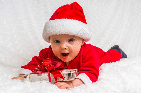 带着礼物躺在白毯子上的可爱的圣诞女图片
