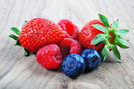 木质背景中的草莓蓝莓和覆盆子图片