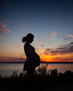 一名孕妇的剪影在日落的图片