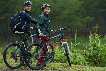 亚洲年轻夫妇在森林路上骑自行车图片