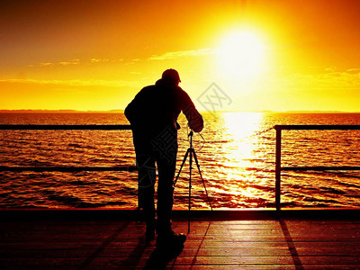摄影师在码头板末端用镜子相机和三脚架拍照秋天有雾的日出在图片