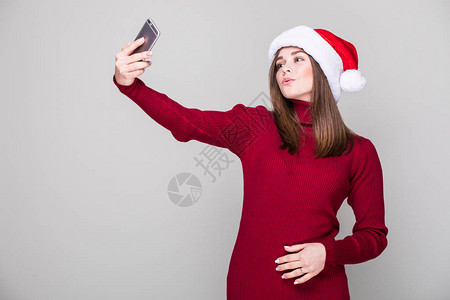 女人在电话上自拍和圣诞帽子握图片