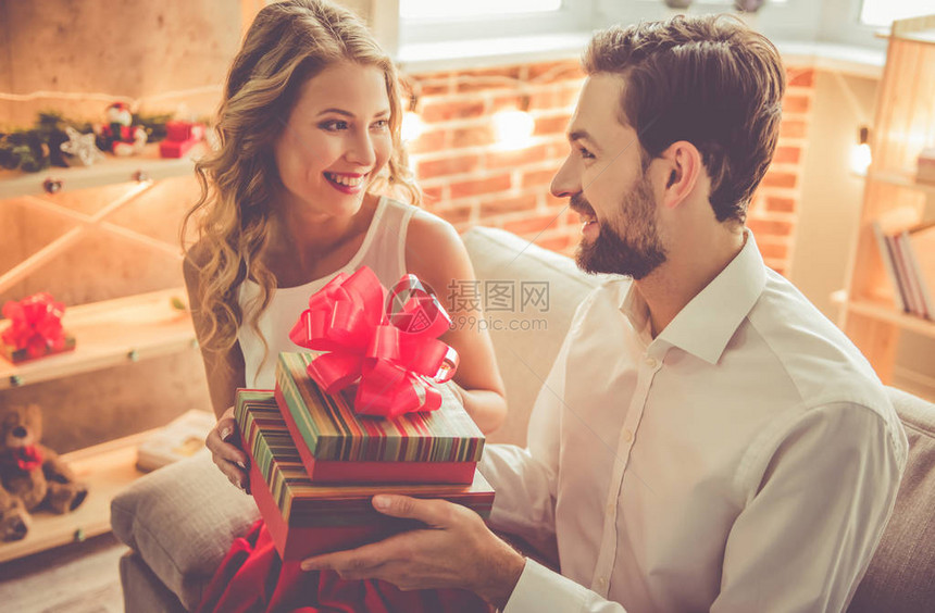 美丽的年轻夫妇在家中庆祝时拿着礼物图片