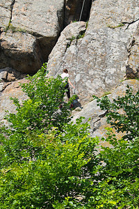 女子攀岩者爬上岩石图片