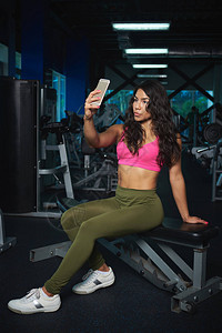 运动型女孩用智能手机拍自然后在健身房锻图片