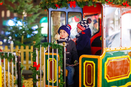 两个小孩男在圣诞游乐场或市场的旋转木马上图片