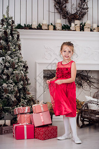 穿着红色晚礼服的漂亮小女孩在圣诞树上穿着红色圣诞图片