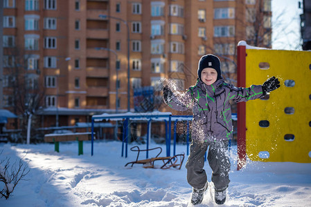 男孩在雪地里跳跃快乐的孩子在冬季城市户外散步快乐的孩子微图片