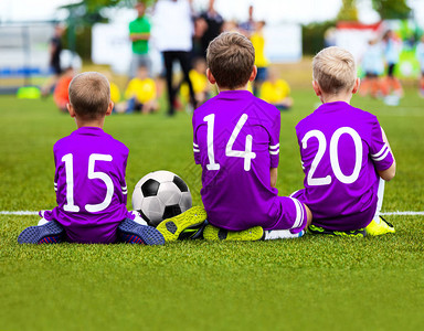 儿童足球队比赛孩子们的足球比赛坐在球场上的年轻足球运动员穿着紫色足球图片