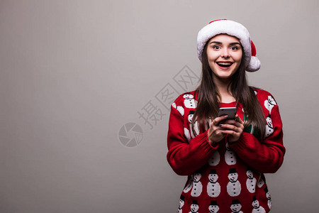 美丽的女孩模特穿着圣塔帽和圣诞节毛衣在灰色的图片