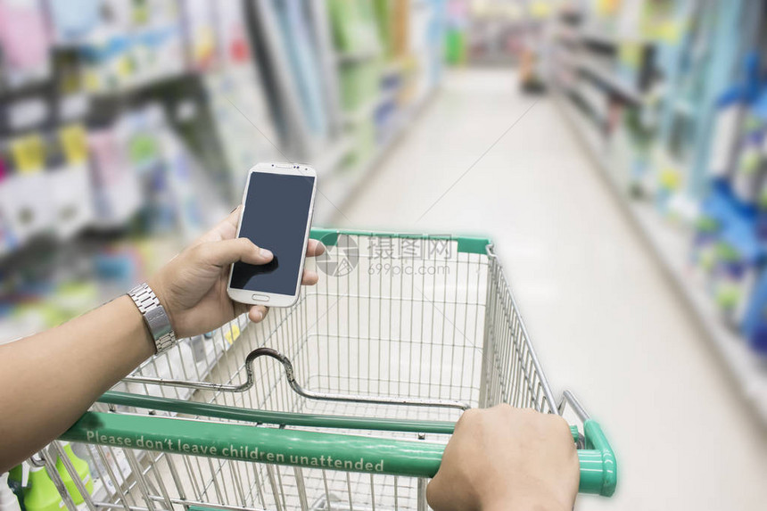女在超市检查智能手机购物图片