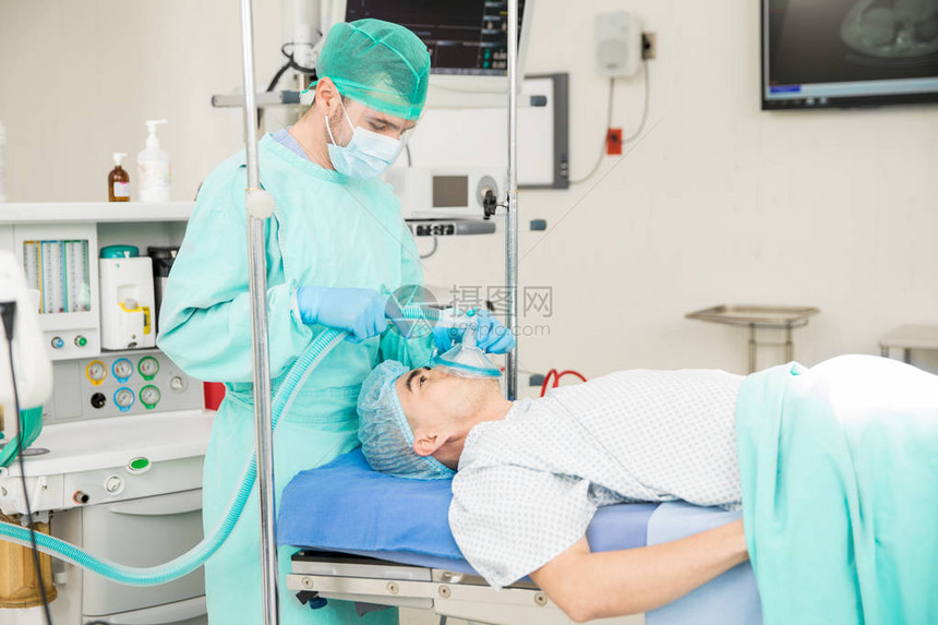 一名男麻醉师在手术前服用镇静剂的病人身上工作图片