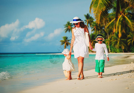 母亲和两个孩子在热带海滩上行走图片