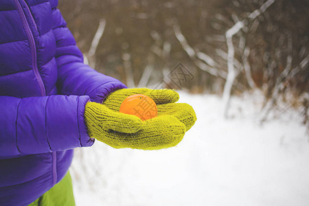 身手温暖的绿手套中的女在雪地背景图片