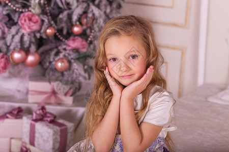 美丽的圣诞装饰品的甜美女孩圣诞树上穿着晚图片