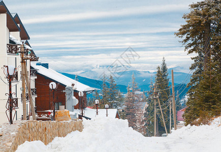 风景雪覆盖的房子靠近森林和山丘图片