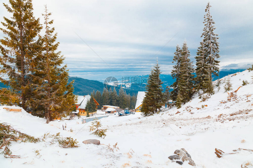 风景雪覆盖的房子靠近森林和山丘图片