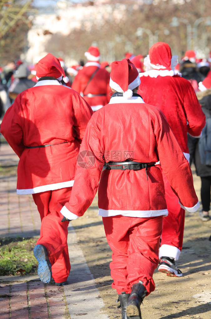 人们在圣诞节期间在城市的公园里与圣诞老人一起跑步的体图片