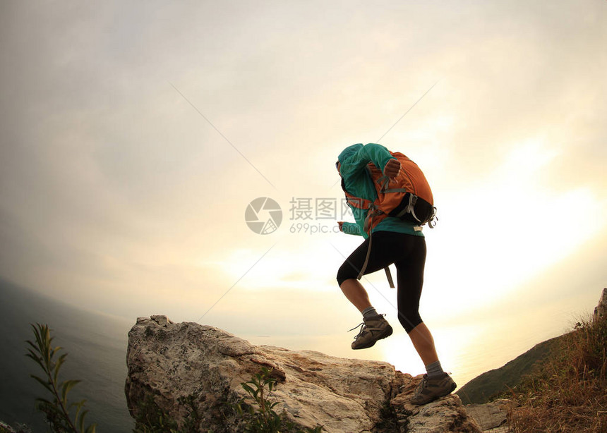 在海边山峰上成功的徒步旅行者图片