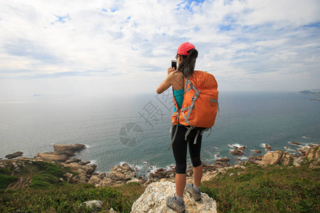 女登山者站在海边山峰上用数字平板图片